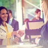 Two women shaking hands at a front counter