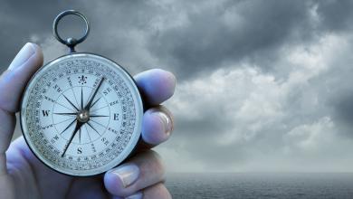 hand holding a compass with a stormy ocean background